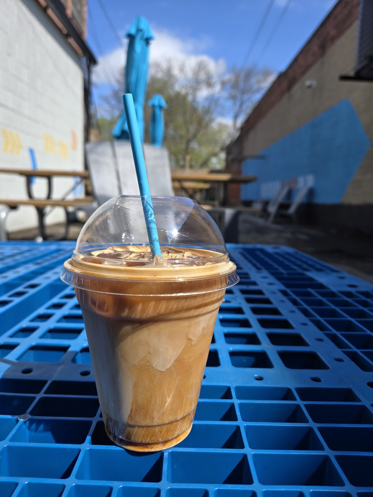 An iced coffee with milk on a blue patio table.