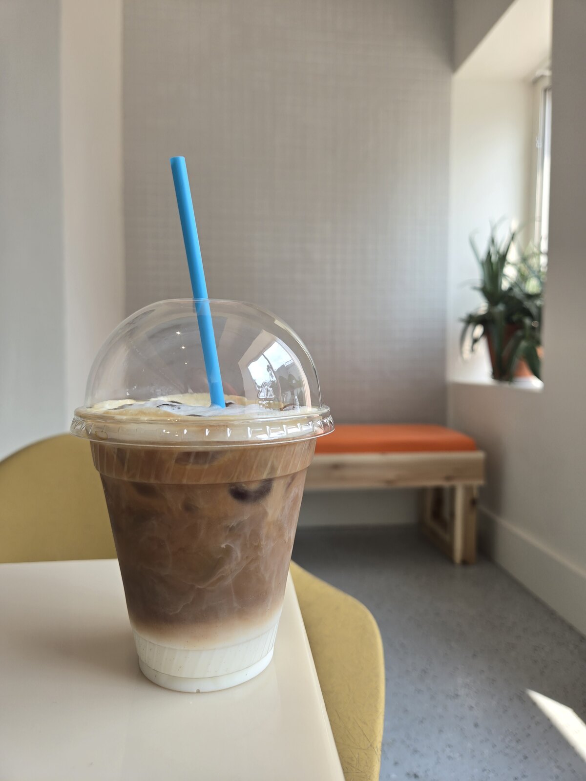 An iced coffee with milk in a clear cup on a café table.